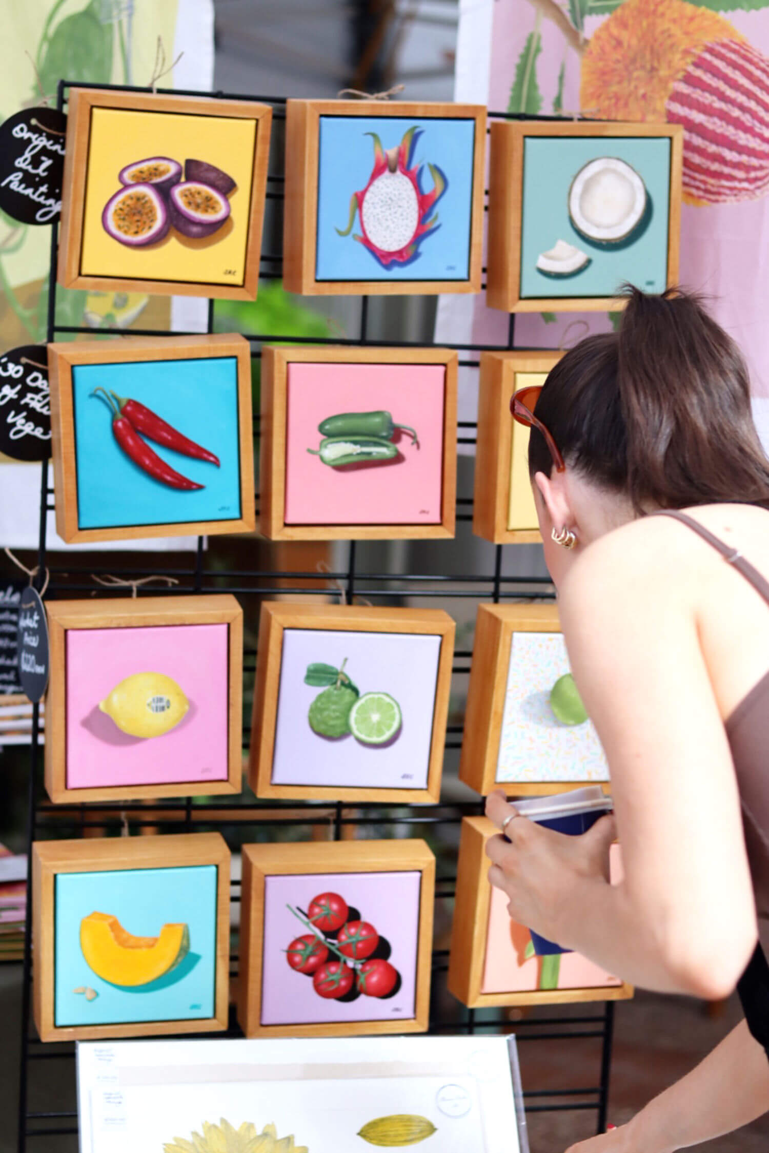 Woman looking at mini framed artworks of food at The Market Folk Brisbane Markets for Creatives